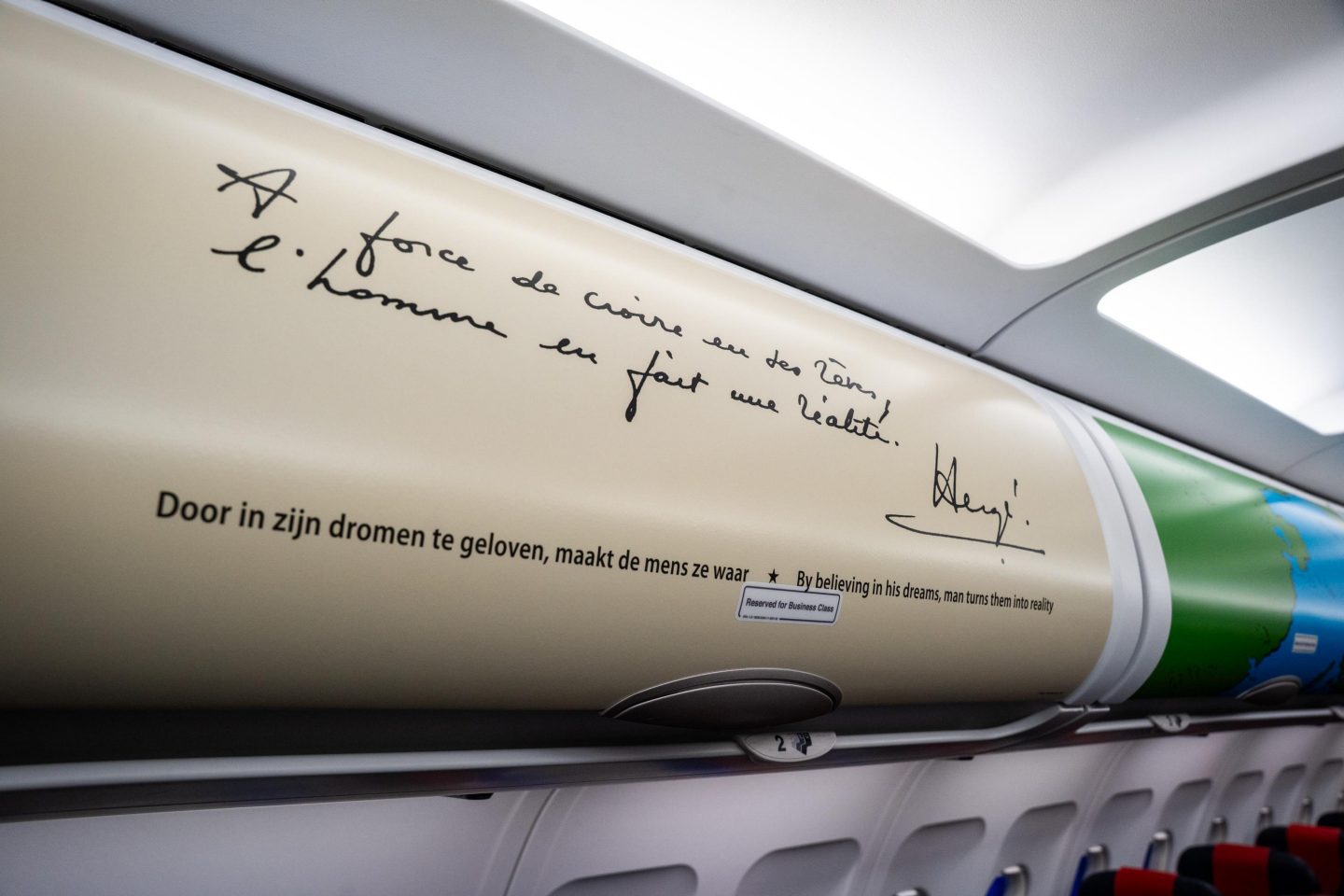 Airplane overhead bin displaying a Hergé quote.