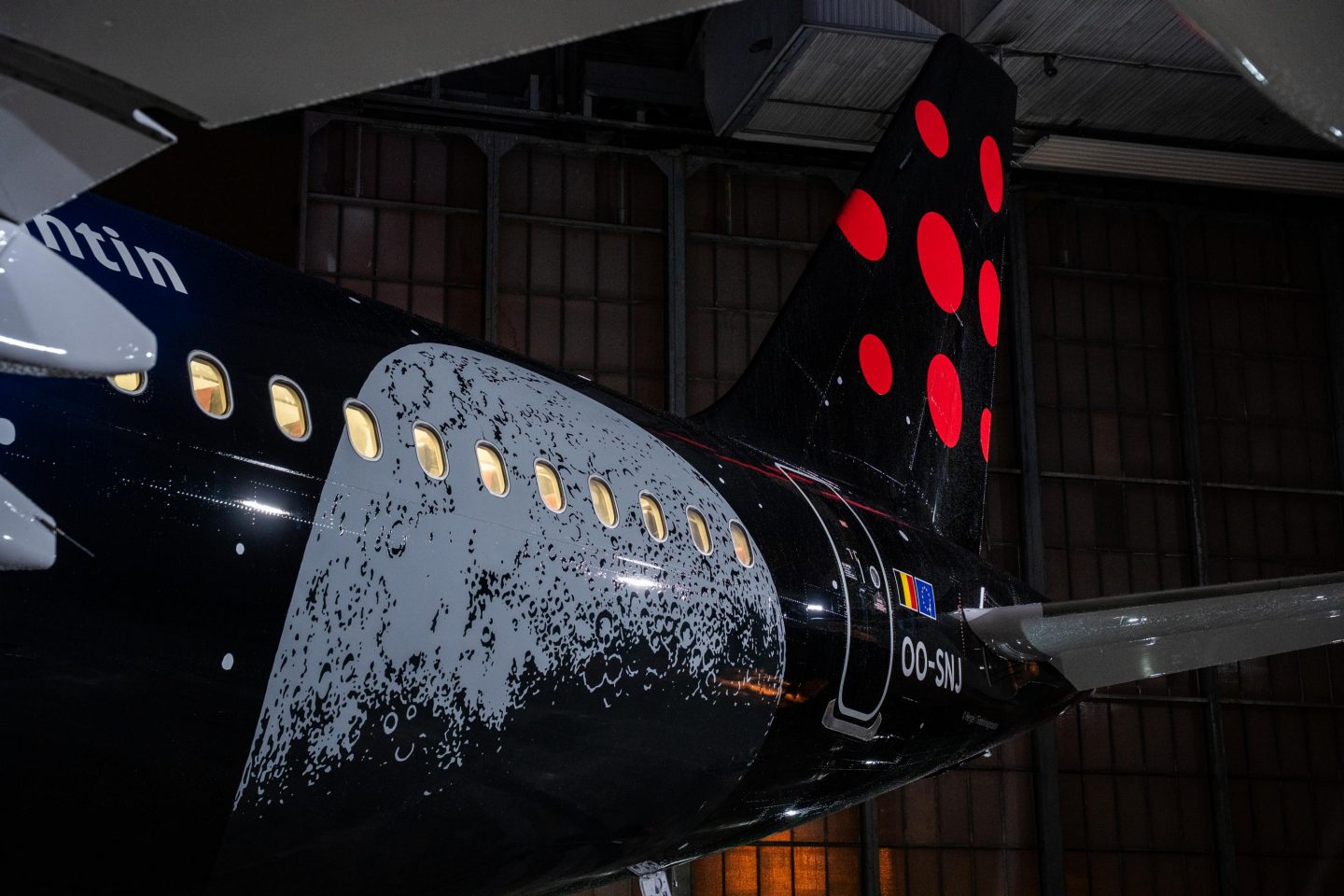 Airplane rear fuselage and tail painted black with a moon surface graphic and red dots