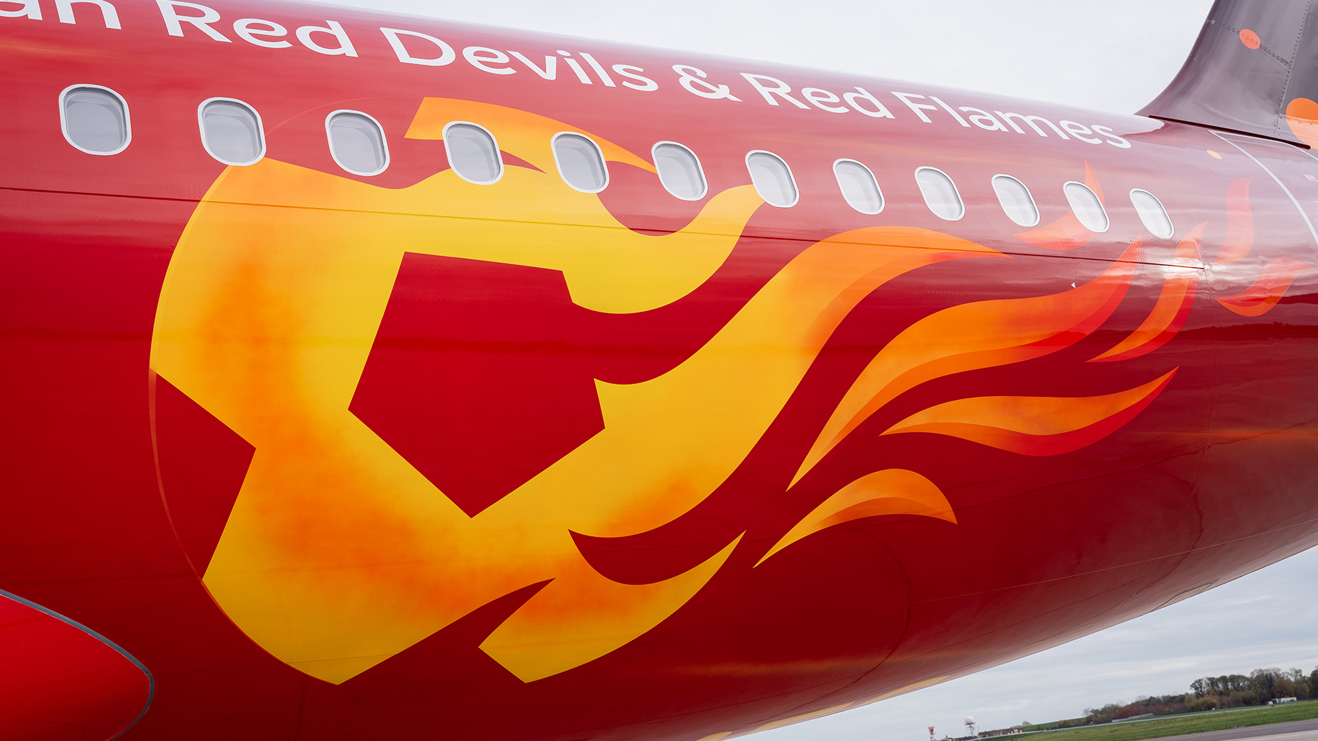 Close-up of a red airplane fuselage with a yellow flame graphic and Red Devils and Red Flames text.