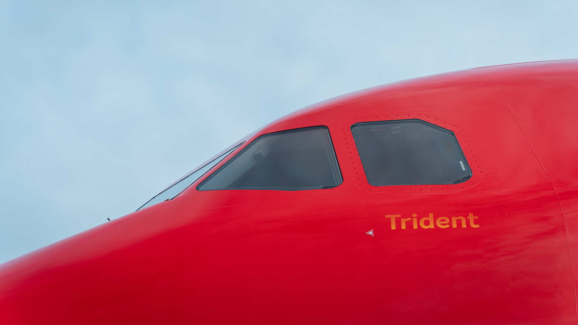 Close-up of a red airplane nose with yellow Trident text.