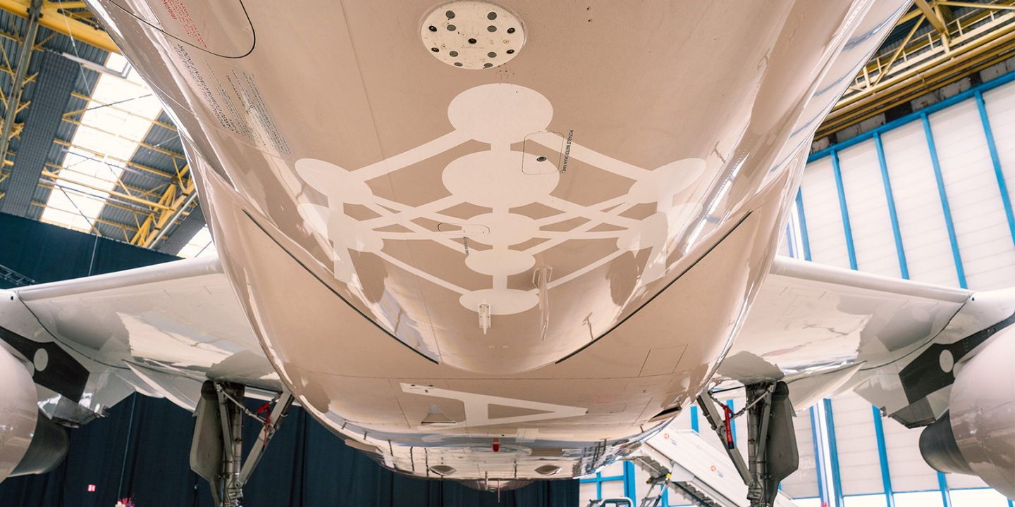Underside of an airplane featuring a white Atomium design.