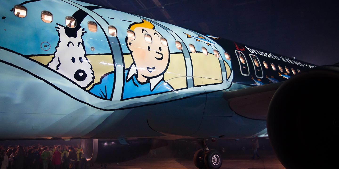 Close-up of the Rackham aircraft fuselage featuring Tintin and Snowy looking out of painted porthole windows.